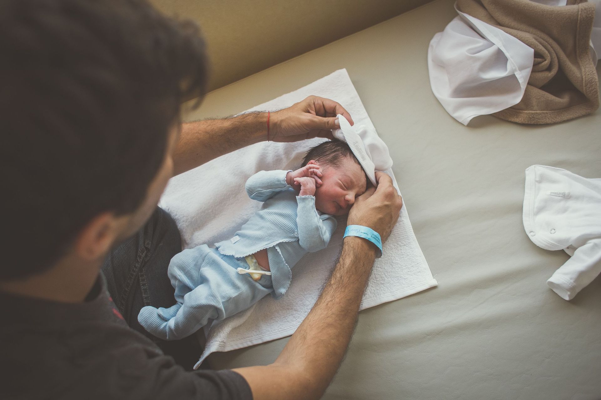Un hombre le pone un sombrero a un bebé recién nacido.