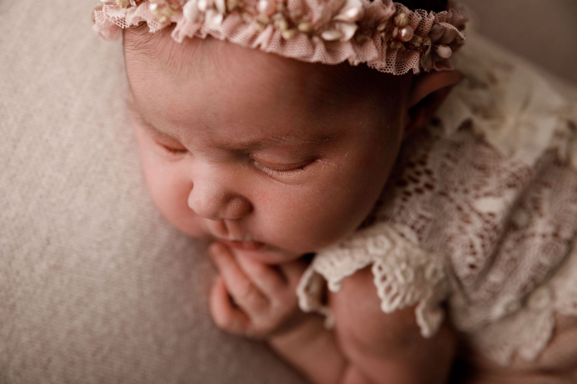 Un primer plano de un bebé con una diadema y un vestido de encaje.