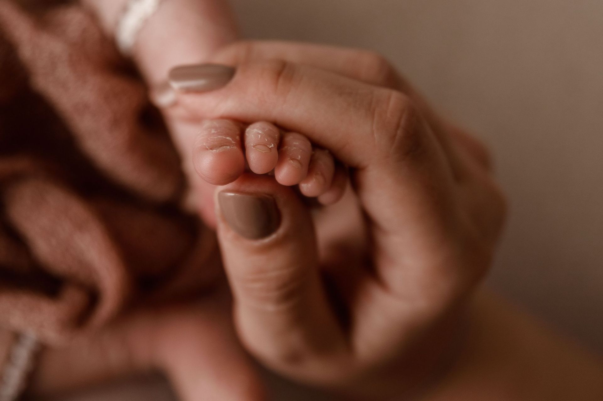 Un primer plano de una mujer sosteniendo la mano de un bebé.