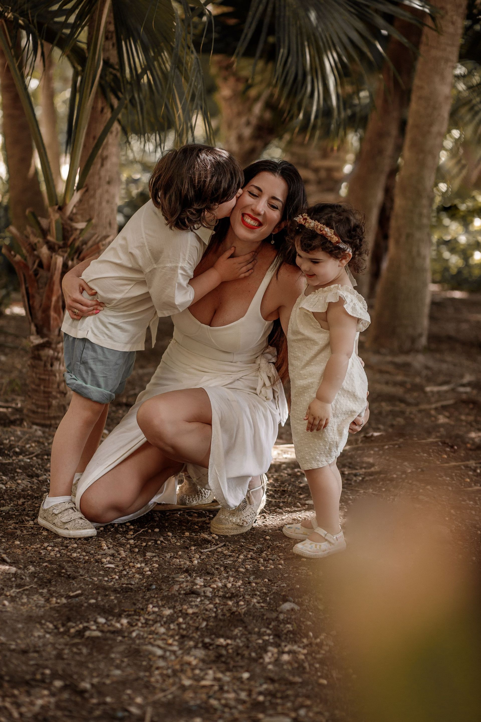 Una mujer está arrodillada con dos niñas pequeñas en el bosque.