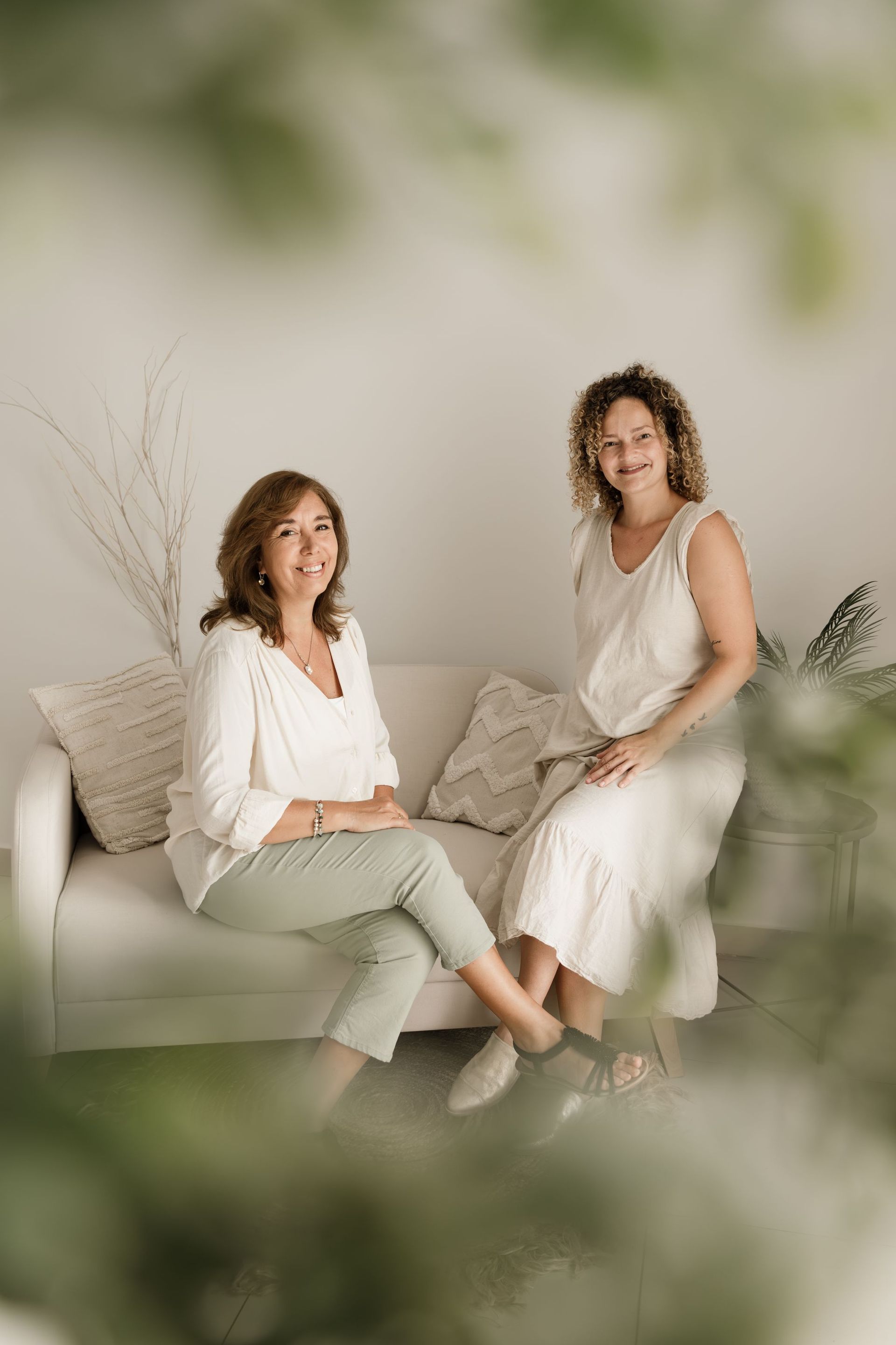 Dos mujeres están sentadas en un sofá blanco en una habitación.
