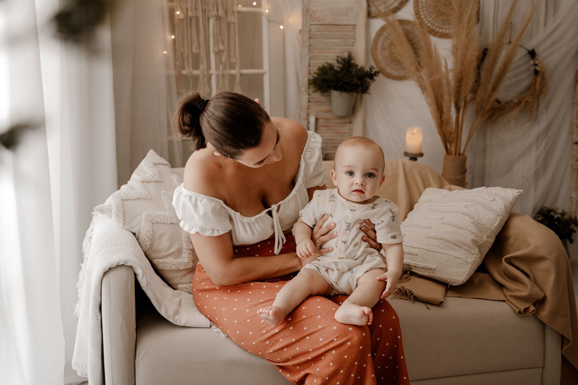 Una mujer está sentada en un sofá sosteniendo un bebé.