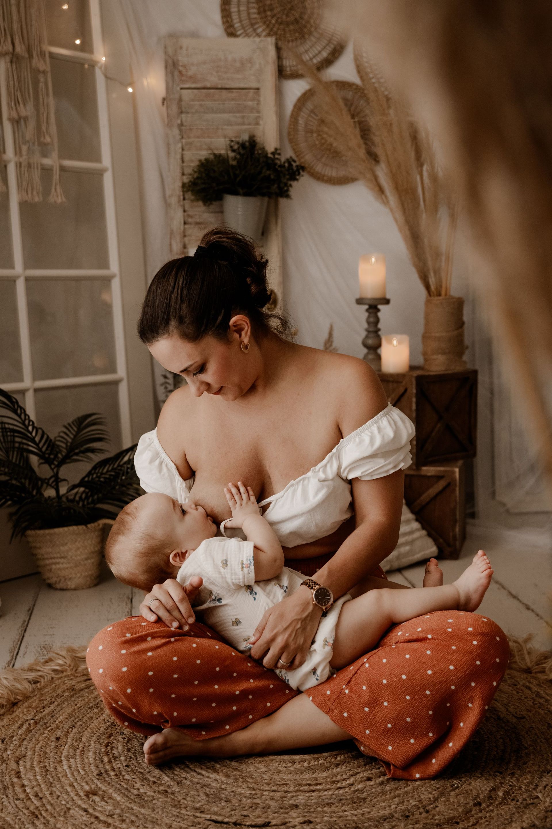 una mujer está sentada en el suelo amamantando a un bebé .