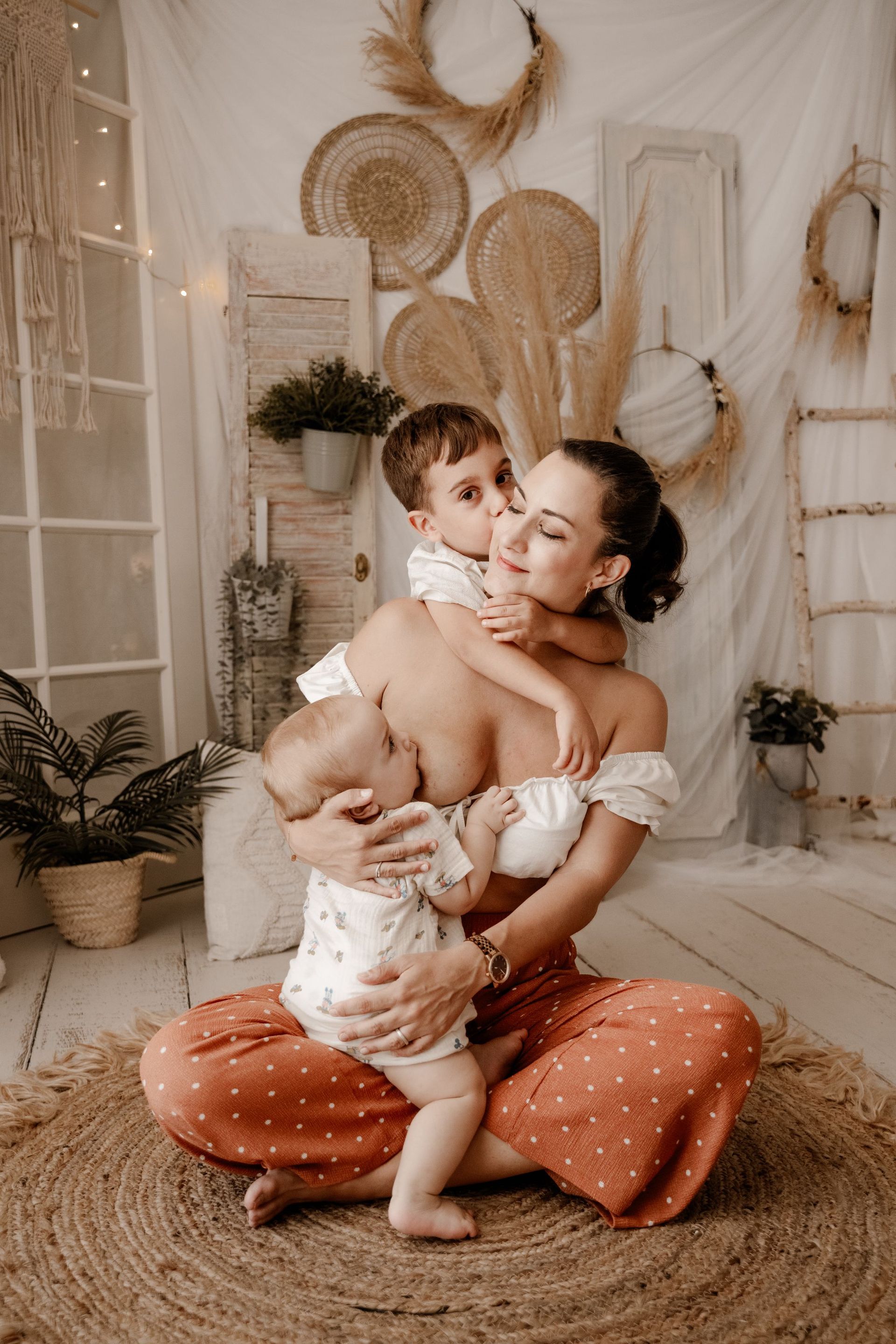 Una mujer está sentada en el suelo amamantando a dos niños.