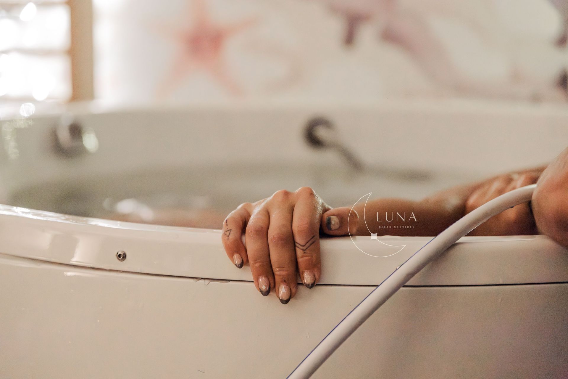 Una mujer está acostada en una bañera sosteniendo una manguera.