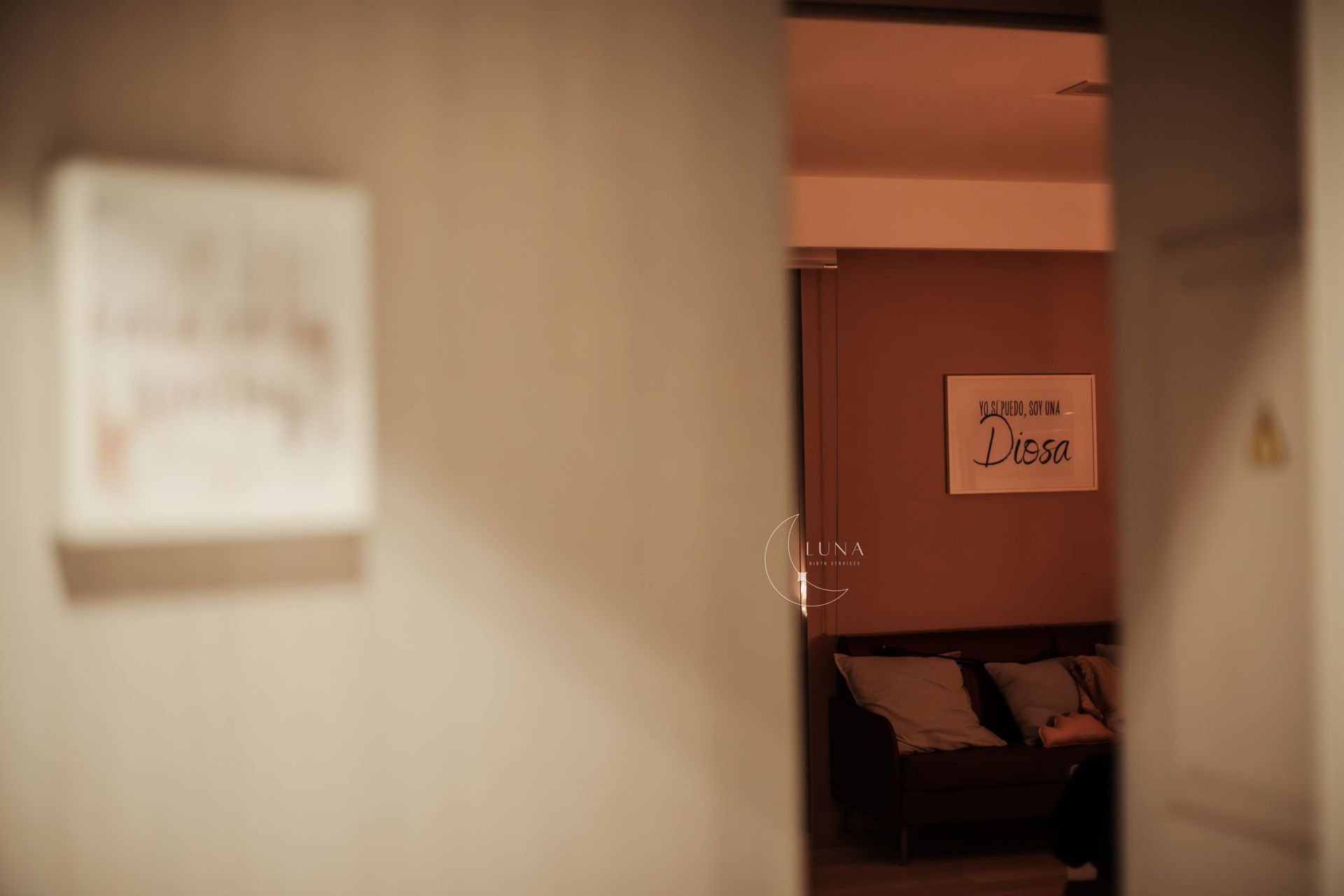 Una puerta que conduce a una sala de estar con un sofá y un cuadro en la pared.