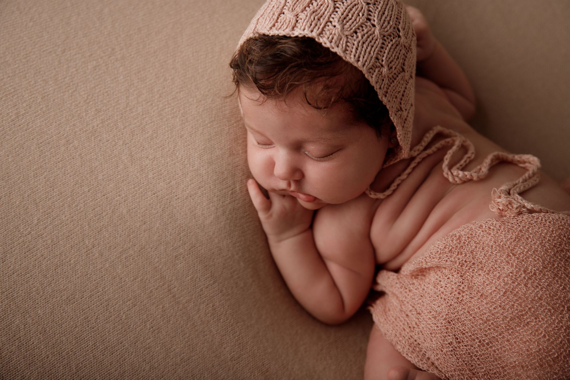 Un bebé recién nacido que lleva un gorro de punto está durmiendo sobre una manta.