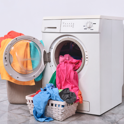A washing machine filled with colorful clothes next to a laundry basket