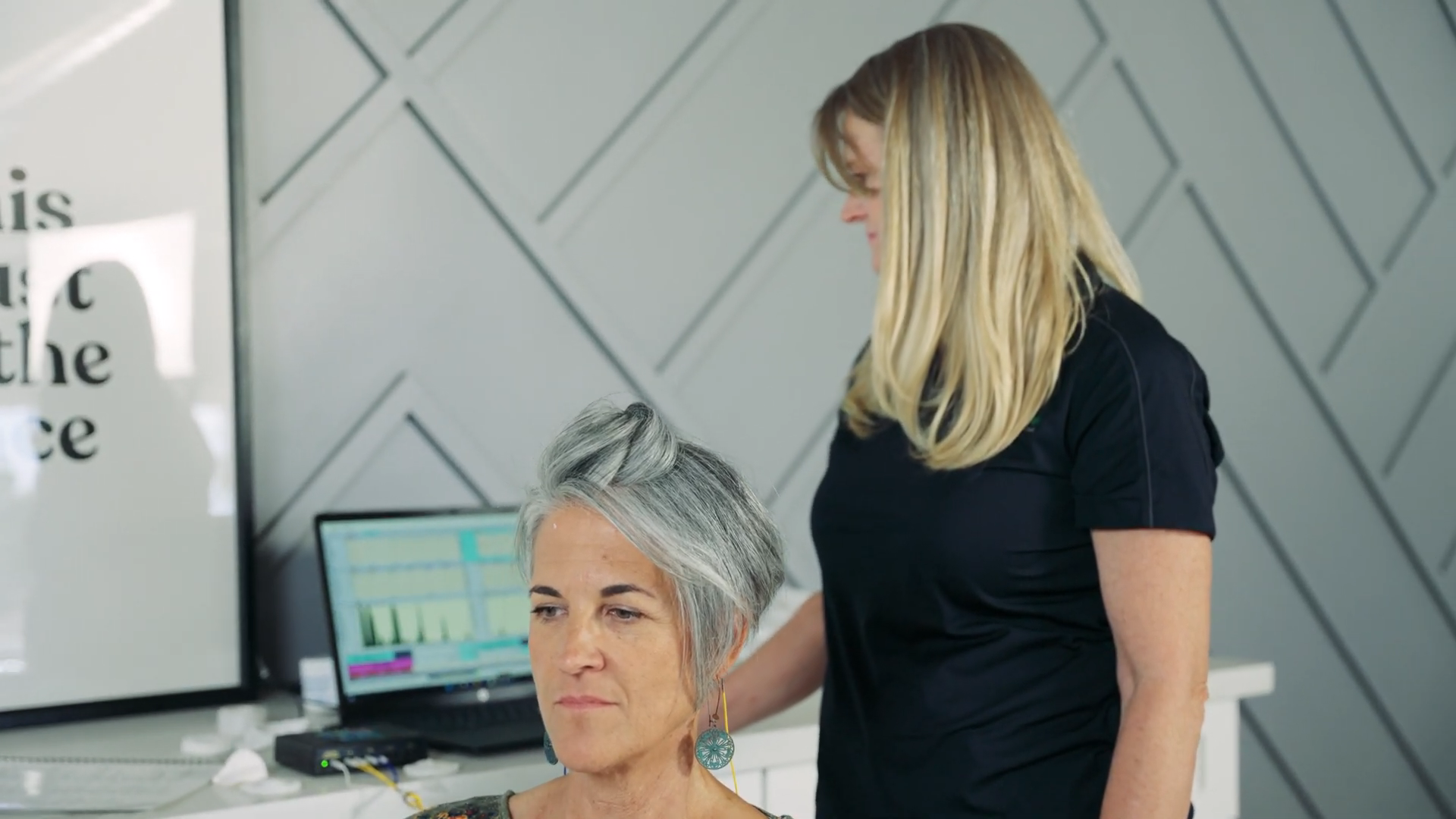 A woman is standing next to a woman with gray hair in a salon