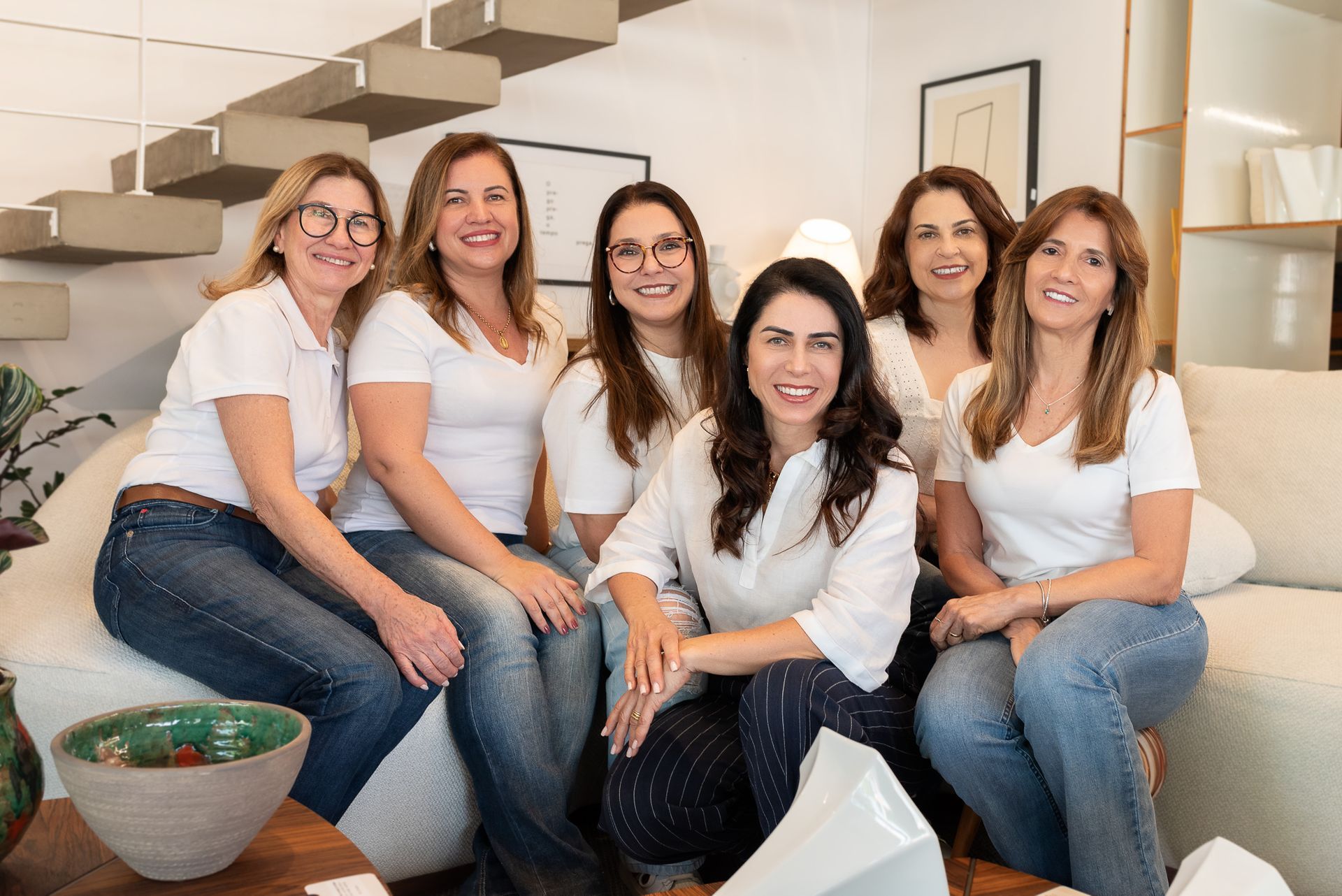 Um grupo de mulheres está posando para uma foto sentadas em um sofá.