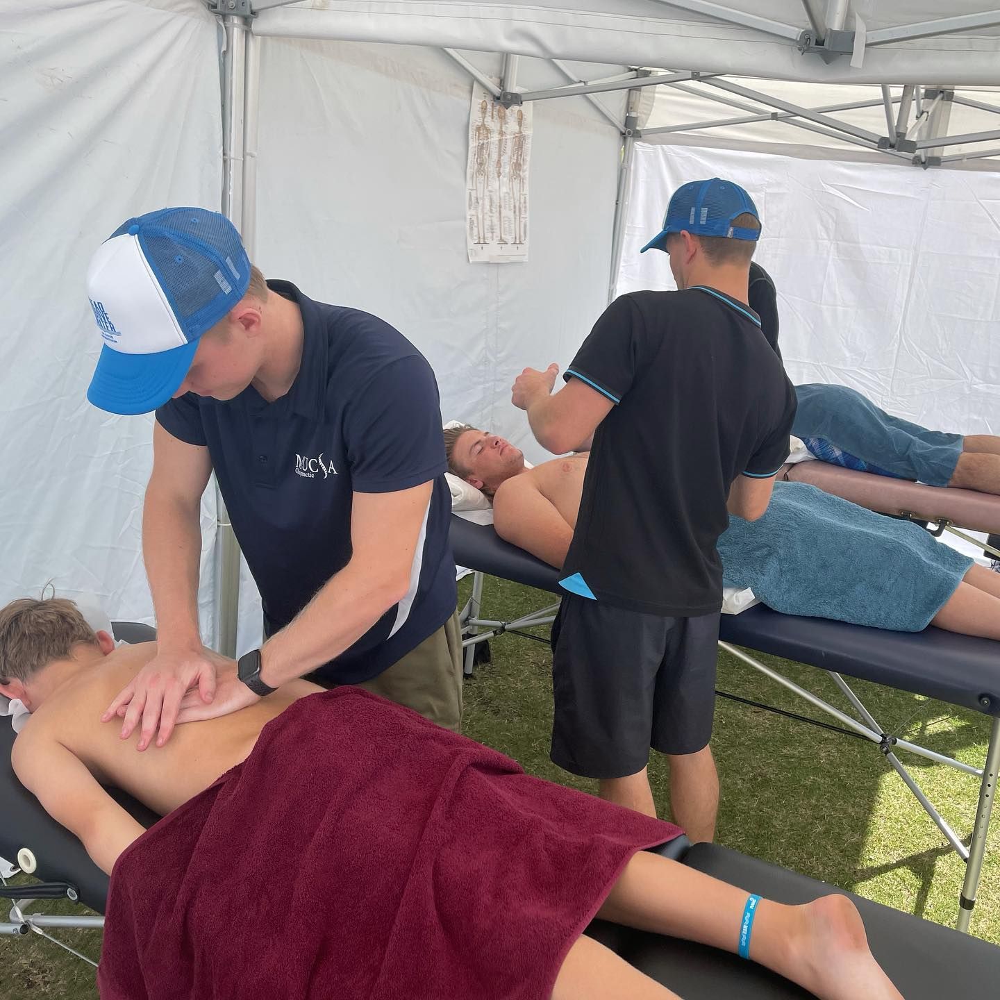 A Man In A Blue And White Hat Is Giving A Man A Massage — Spinal Symmetry In Port Stephens, NSW