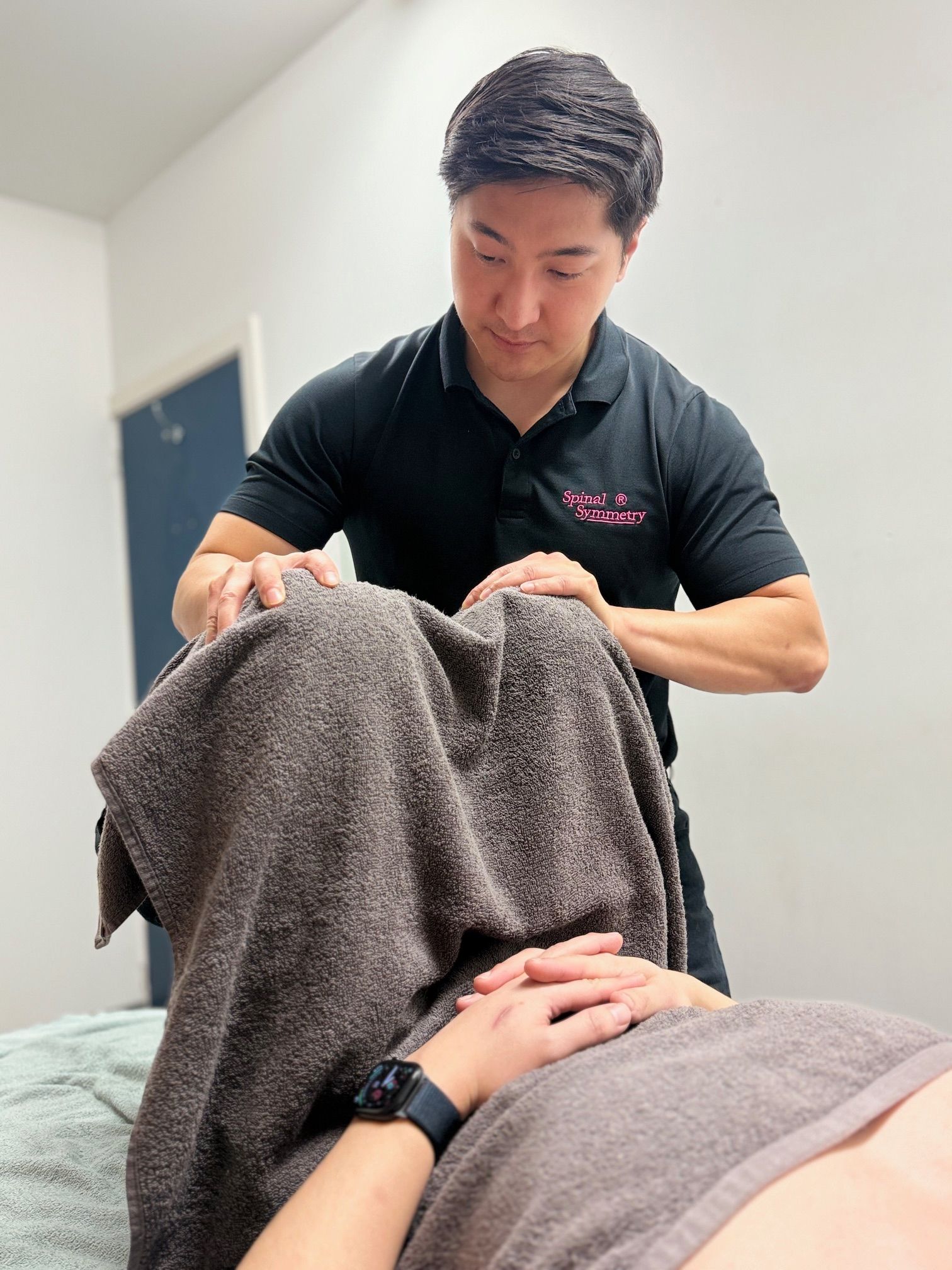 A person receiving face massage, draped by a towel — Spinal Symmetry In Salamander Bay, NSW