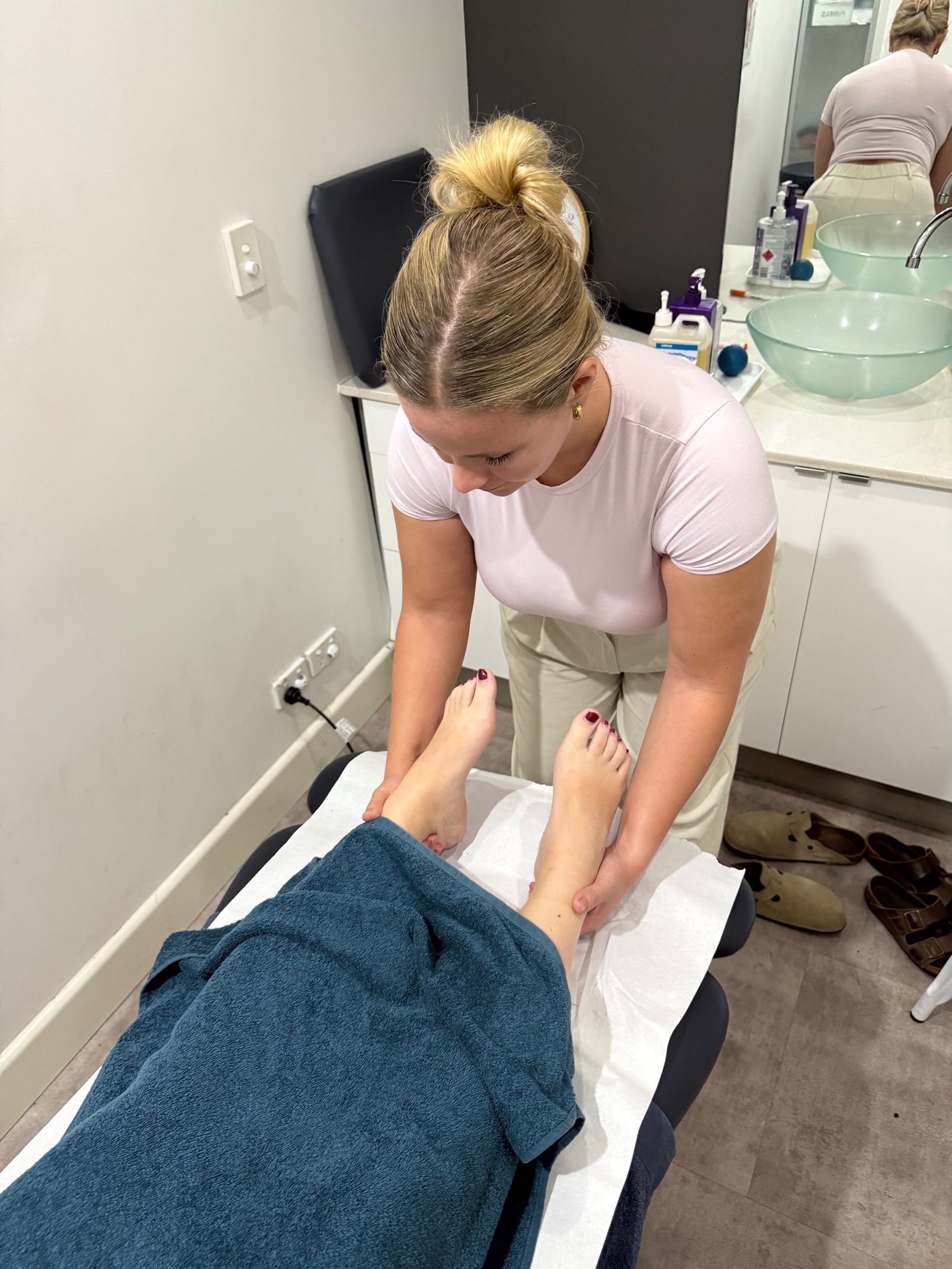 A woman in a pink shirt massaging a woman's ankles— Spinal Symmetry In Pymble, NSW