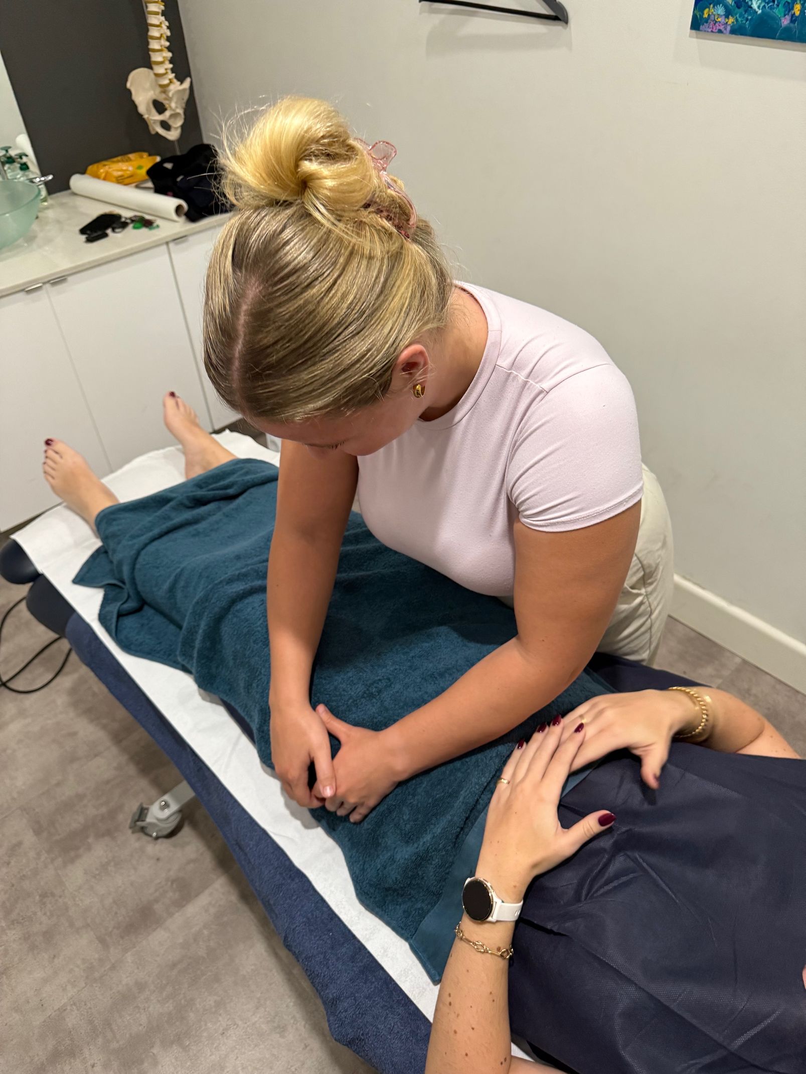 Woman giving abdominal massage to a person lying on a treatment table — Spinal Symmetry in Salamander Bay, NSW