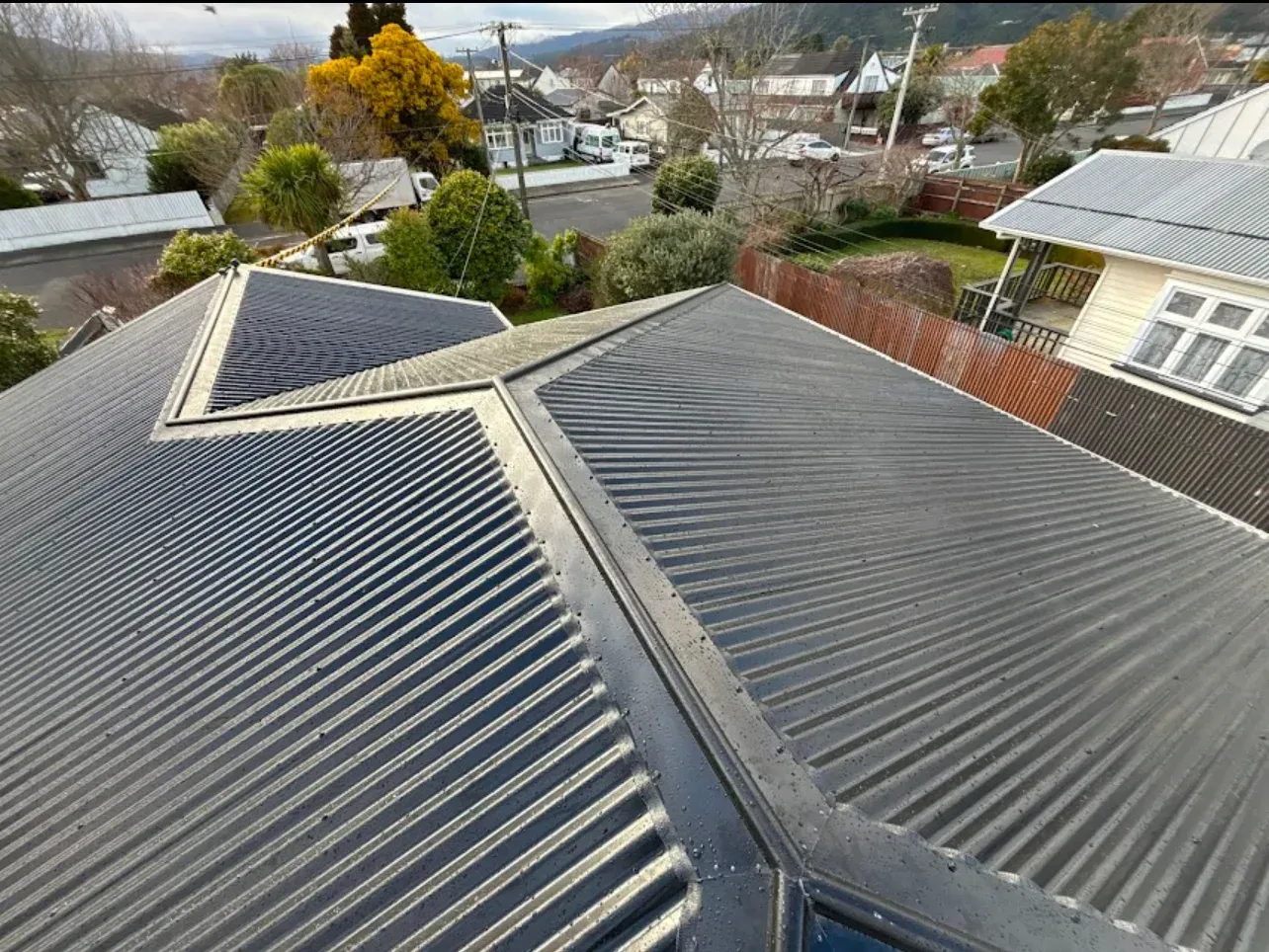 A man wearing a hard hat and safety vest is working on a roof.