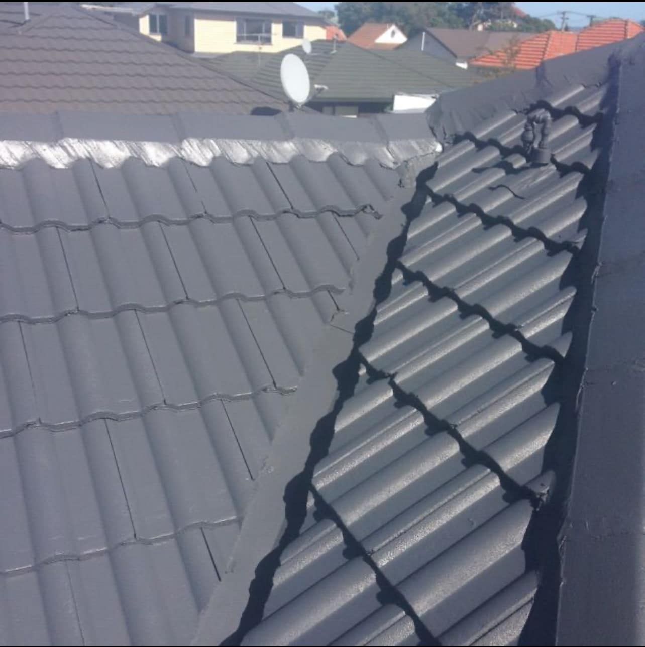 A close up of a red tiled roof with a blue sky in the background.