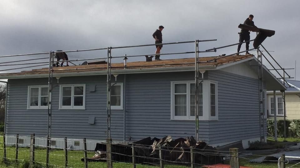 A group of people are working on the roof of a house.