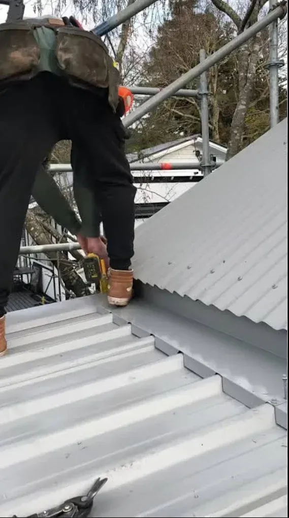 A man is working on a roof with a measuring tape.