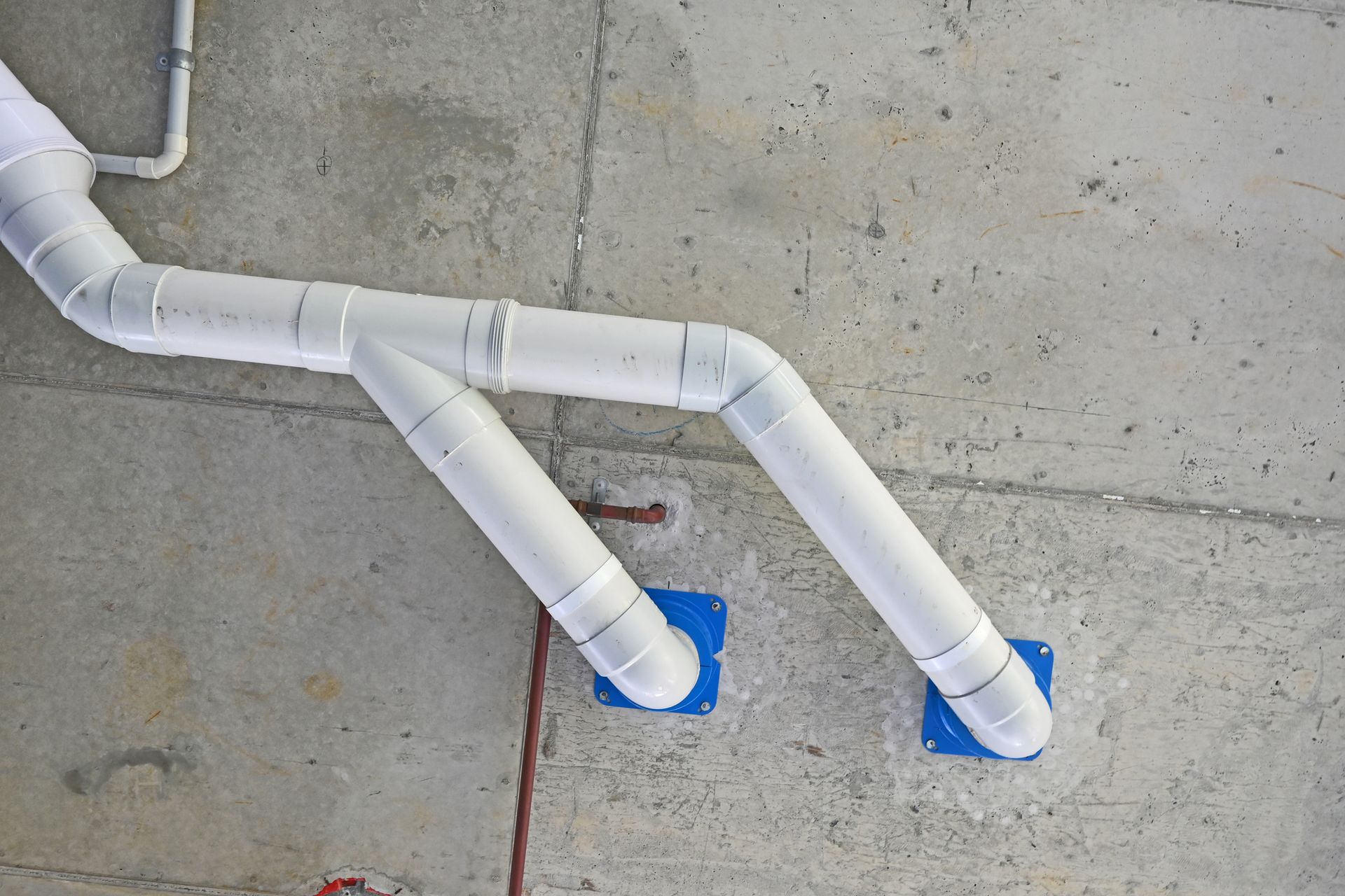 A bunch of white pipes are connected to a concrete wall.
