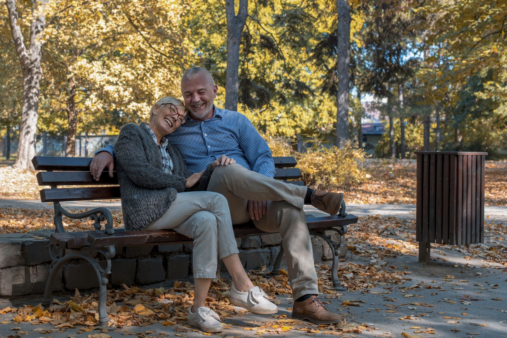 An elderly couple is sitting on a park bench.