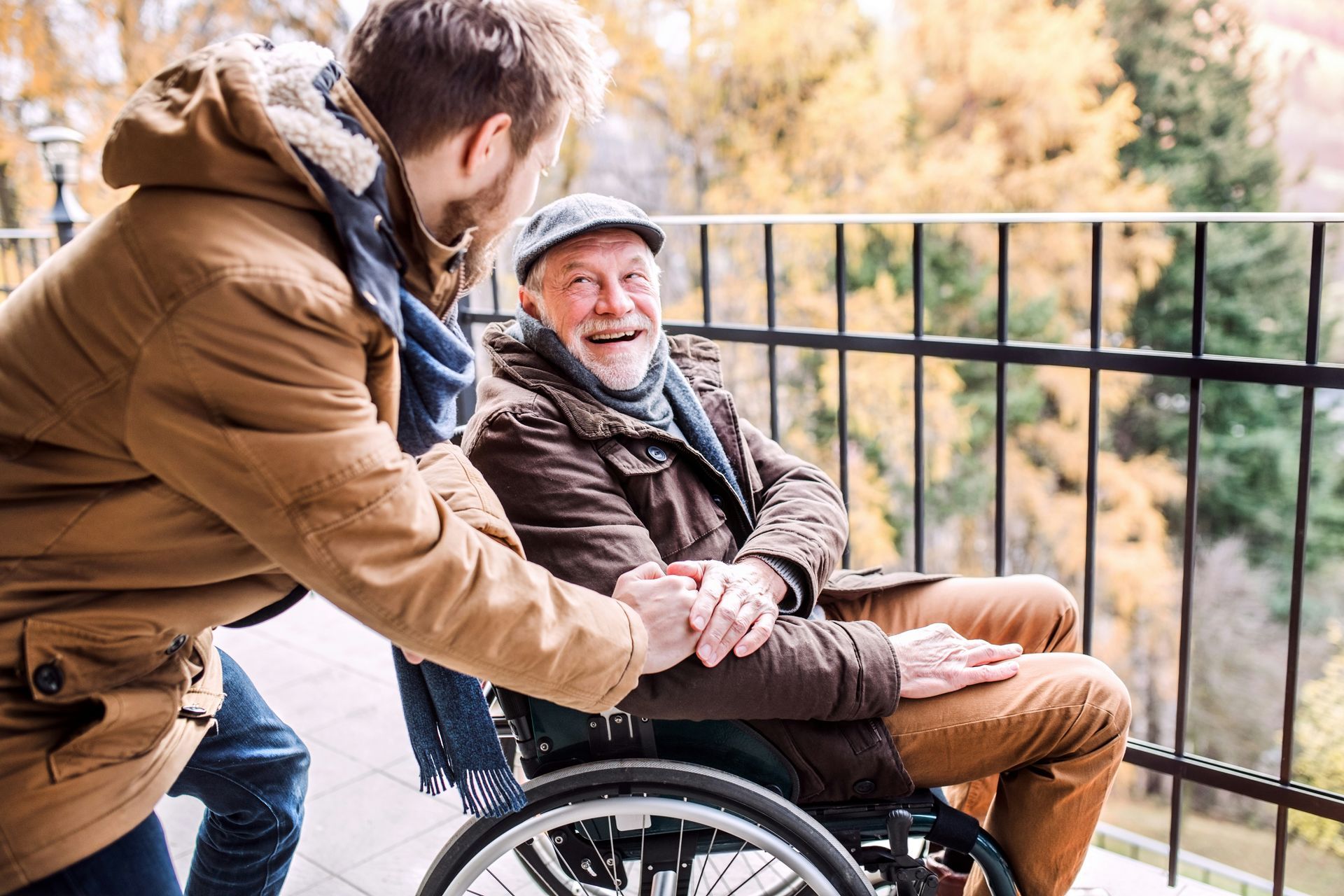 A young man is helping an older man in a wheelchair.
