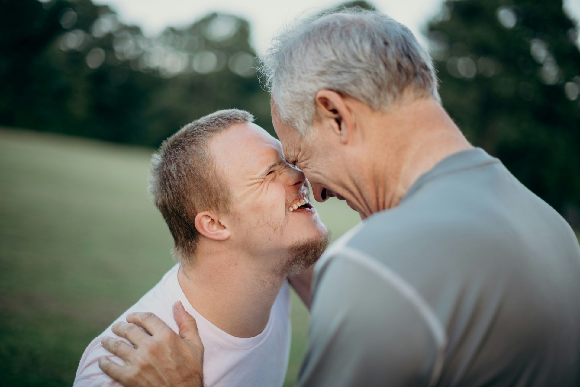 An elderly couple is dancing together in a park.