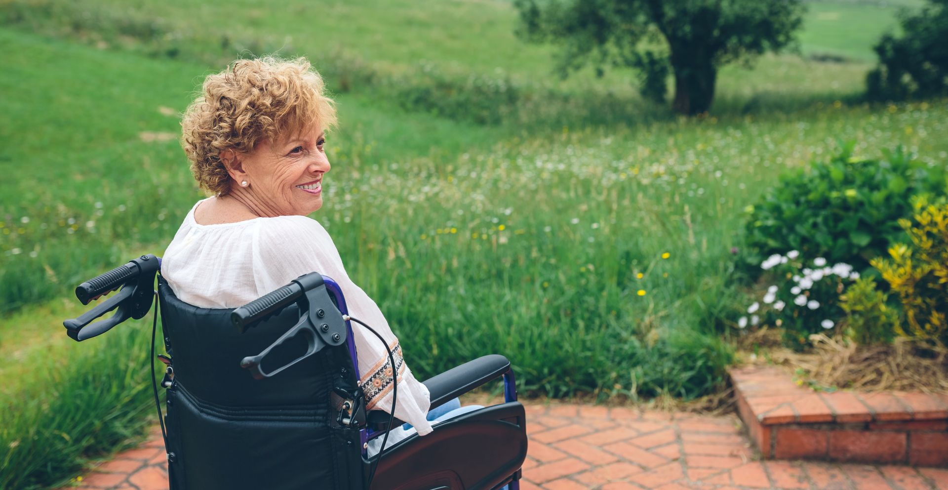 An elderly woman is sitting in a wheelchair in front of a window.