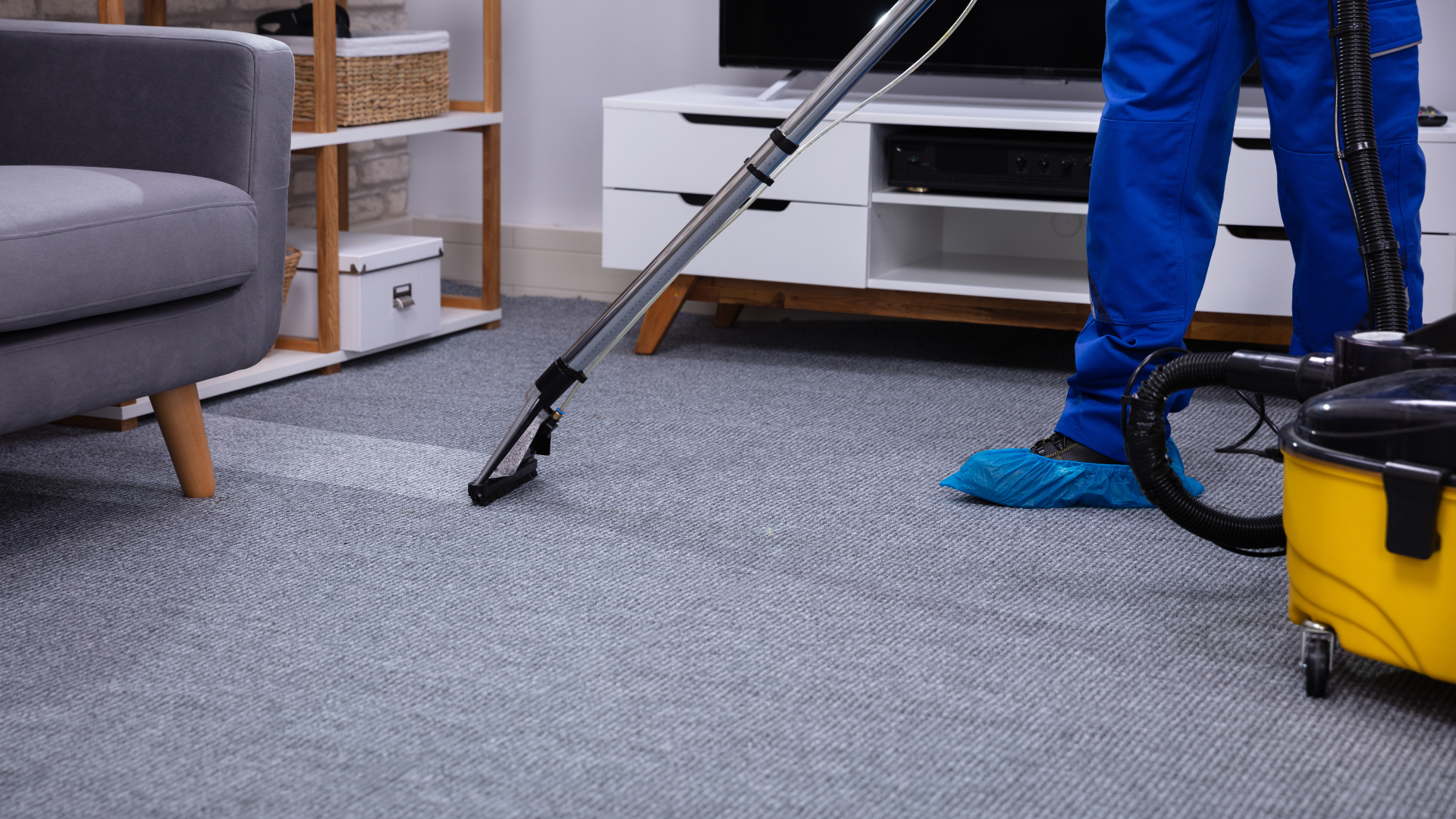 A man is using a vacuum cleaner to clean a carpet in a living room.