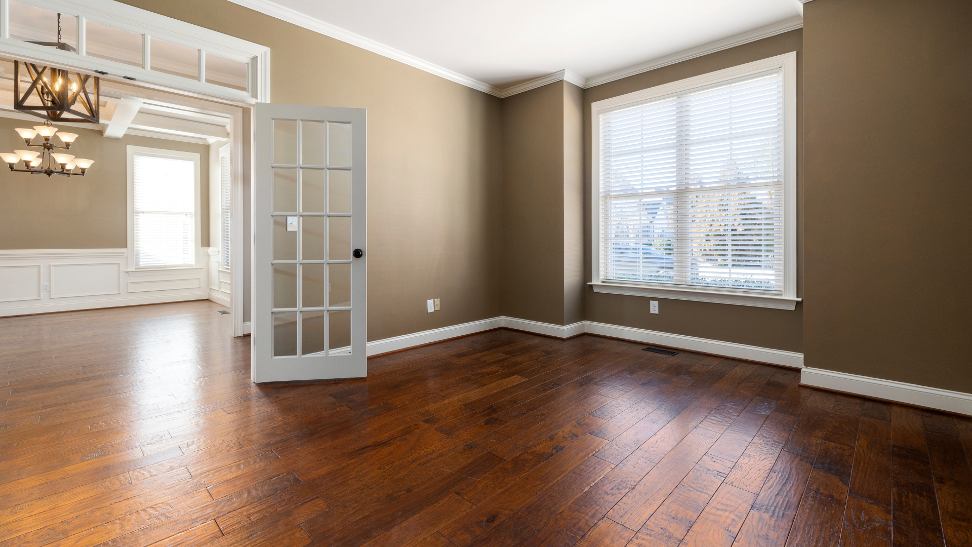 An empty living room with hardwood floors and brown walls.