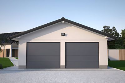 Two-car garage with gray doors, white walls, and a dark roof. Gravel driveway.
