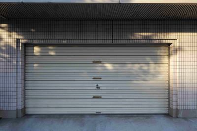 Two-car garage with gray doors, white walls, and a dark roof. Gravel driveway.