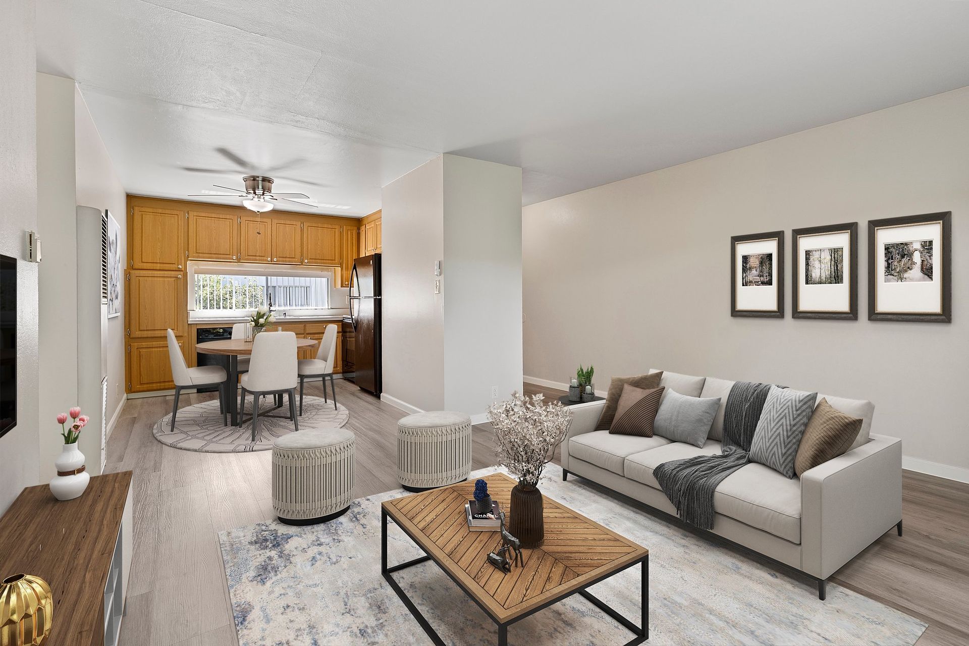 A light-filled apartment featuring a dining area with wooden cabinets and a living room with a beige sofa and wall art at Whispering Oaks in Concord, CA.