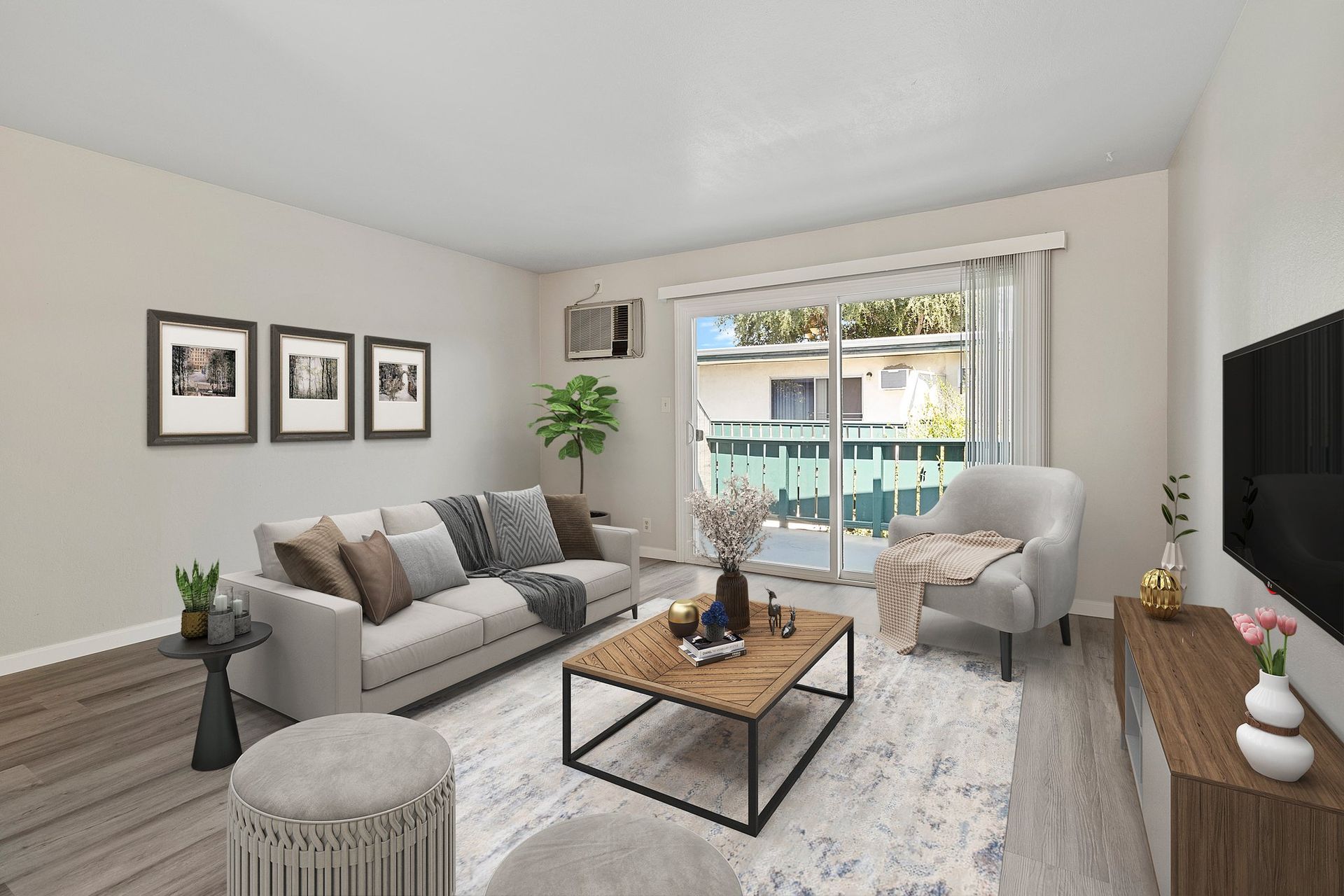 A living room with a gray sofa, wood-frame coffee table, armchair, and sliding glass door leading to a balcony at Whispering Oaks in Concord, CA.