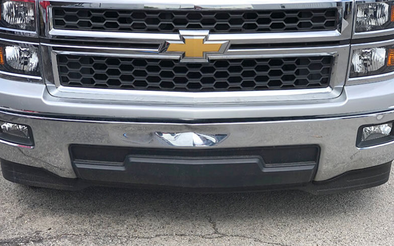 Silver Chevrolet truck front with chrome grill, black bumper, and Chevrolet logo.