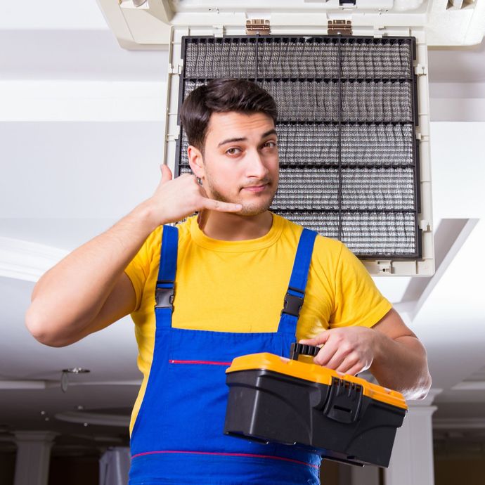 Achoo LLC - A man in overalls is holding a toolbox and making a phone call