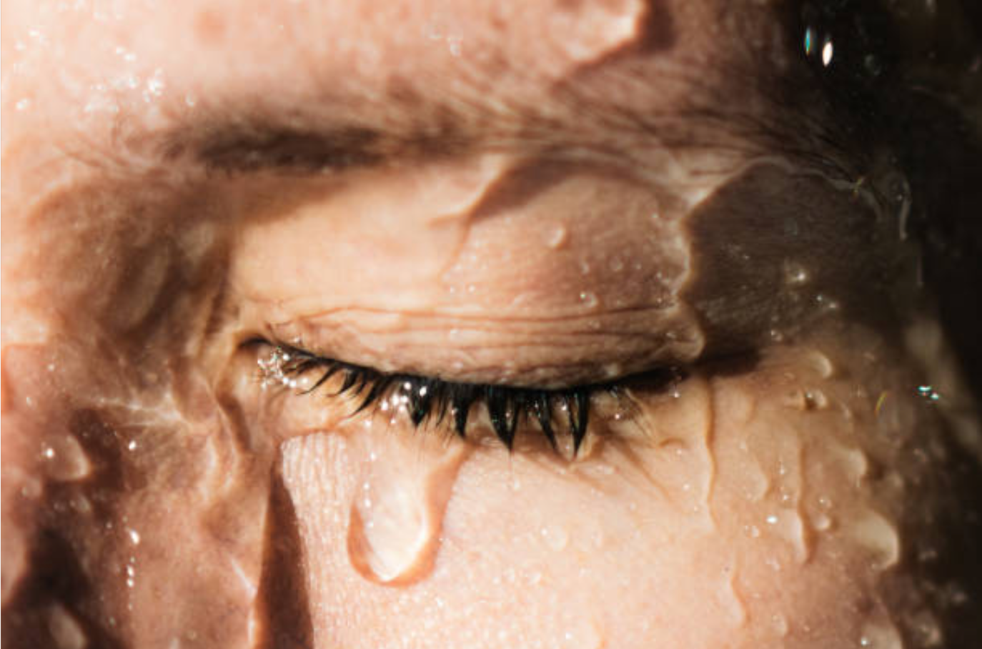 Eine Nahaufnahme des Auges einer Person mit einem Wassertropfen darauf.
