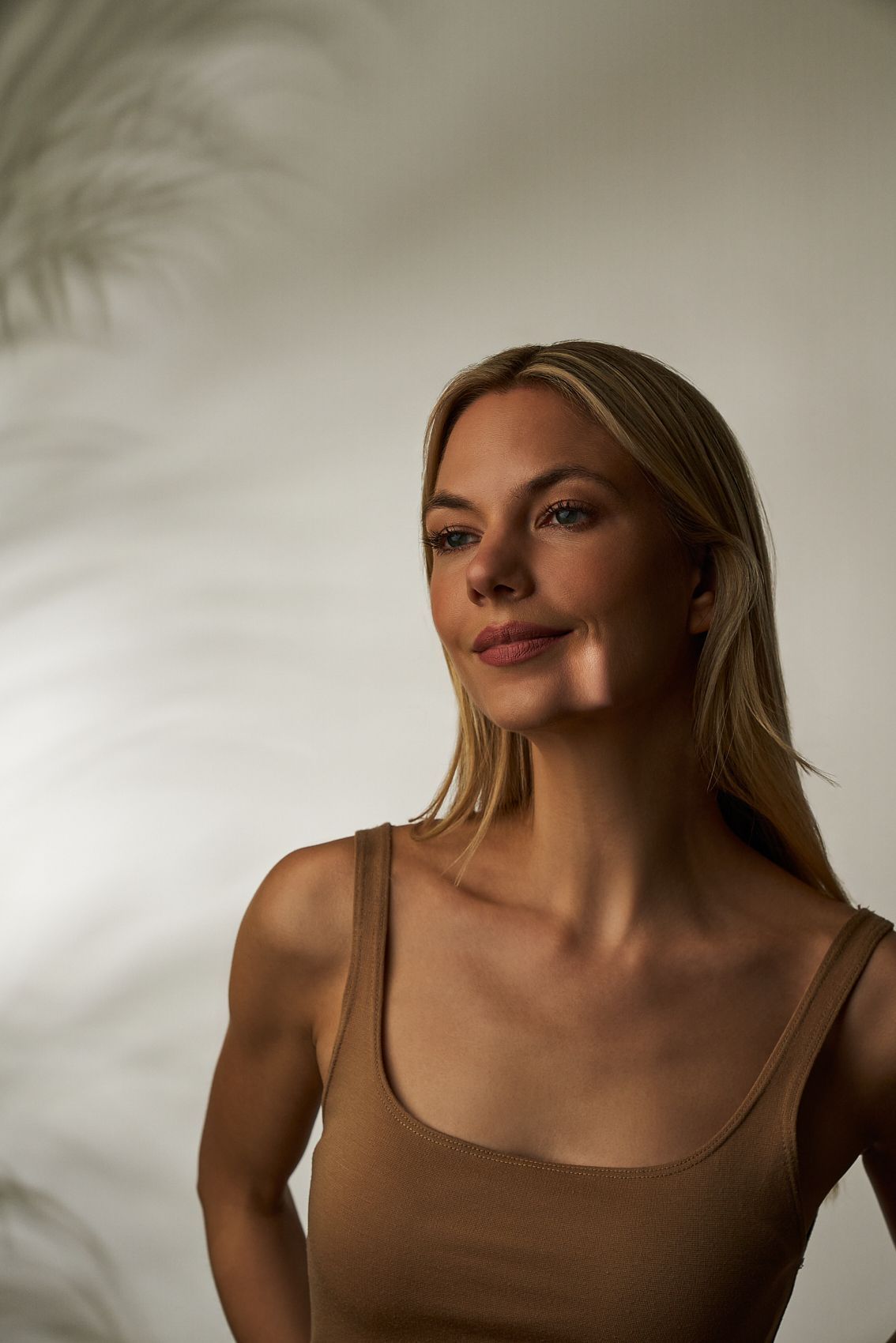 Eine Frau mit langen blonden Haaren trägt ein hellbraunes Tanktop. Brow Lift