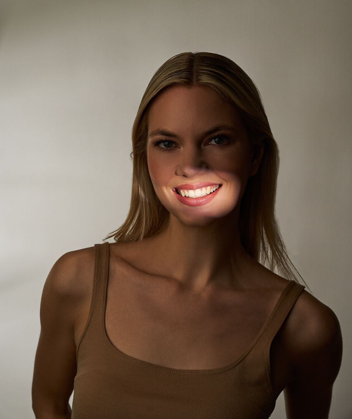 Eine Frau lächelt mit geschlossenen Augen und zeigt ihre weißen Zähne. Hyaluron