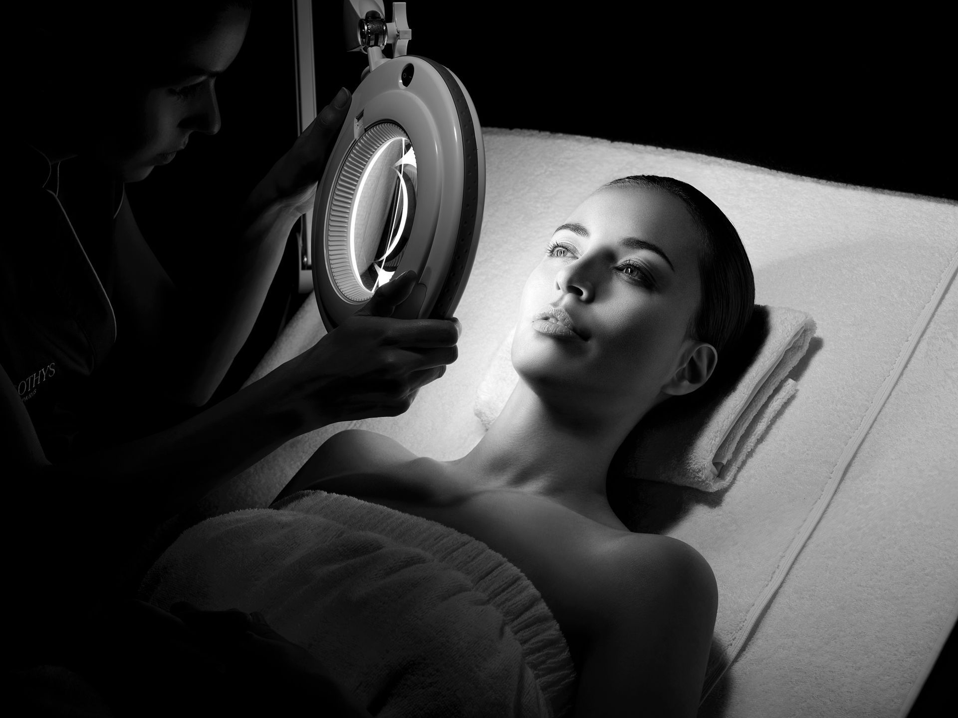 Eine Frau lässt sich im Spa die Gesichtshaut mit einer Vergrößerungslampe untersuchen.