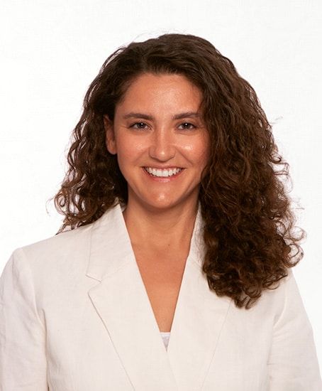 Eine Frau in einer grünen Jacke steht vor einem Baum.