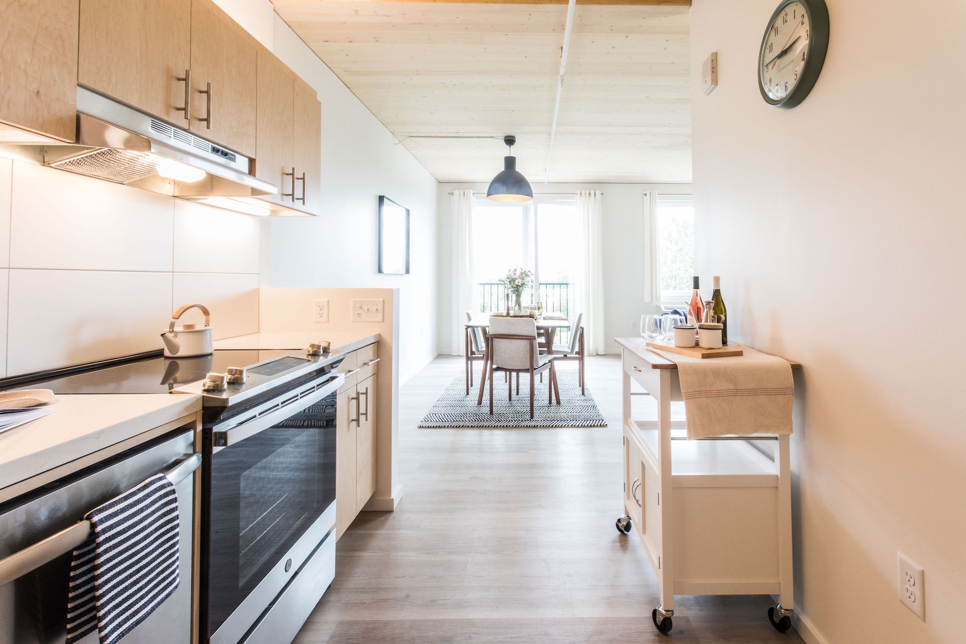 Modern kitchen with stove, cabinets, and dining area beyond.