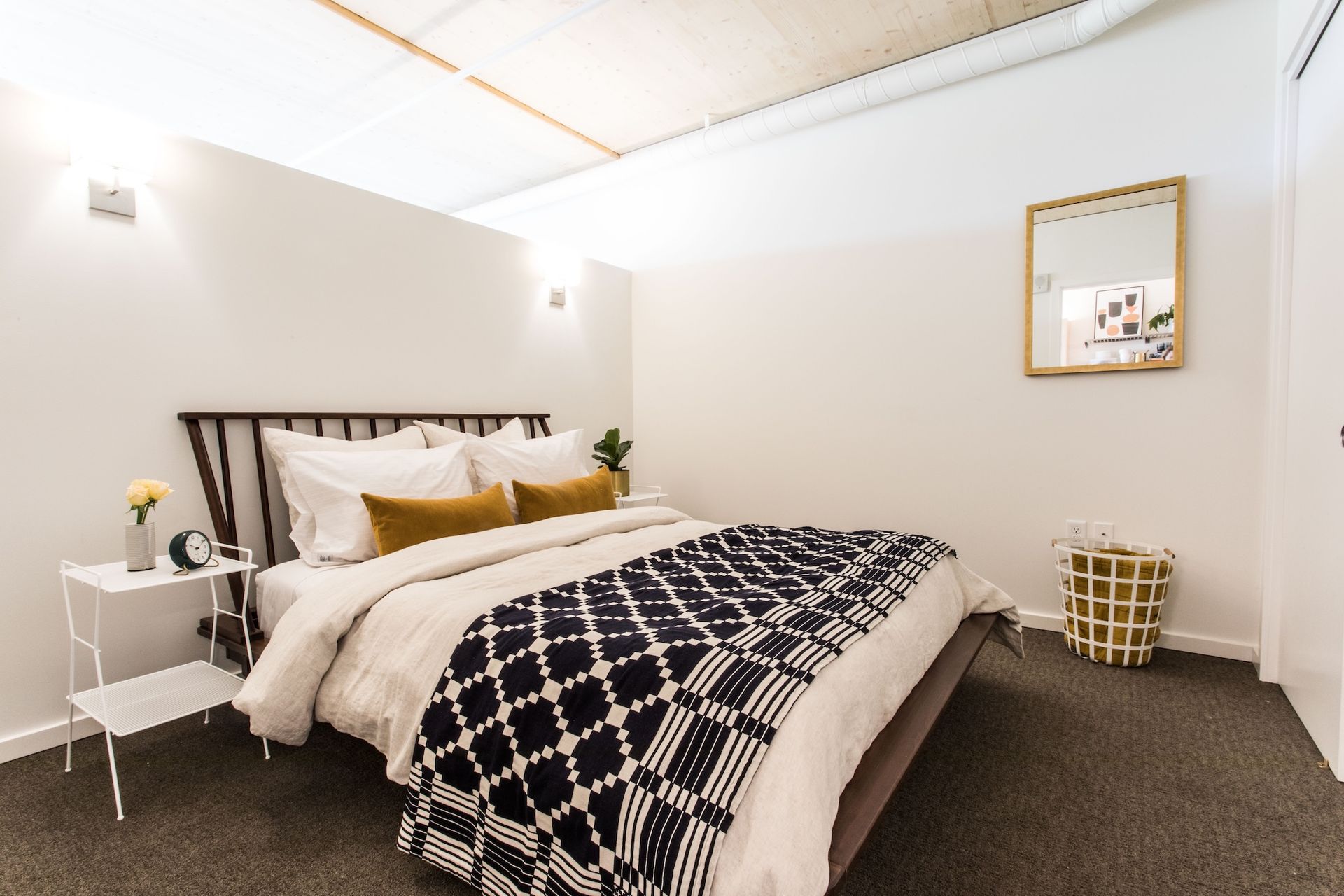 Bedroom with a bed, white walls, and a side table with a flower.
