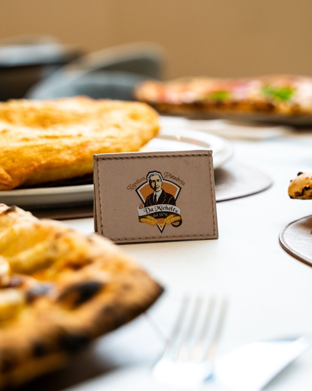 Portafoglio con logo raffigurante un uomo circondato da una pizza su un tavolo bianco.