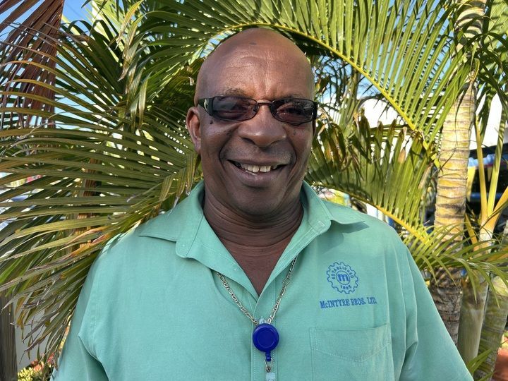 A man in a blue shirt is standing in front of a wall with circles that say honesty and integrity