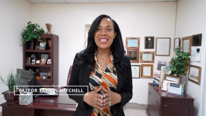 A woman is standing in front of a desk in an office.