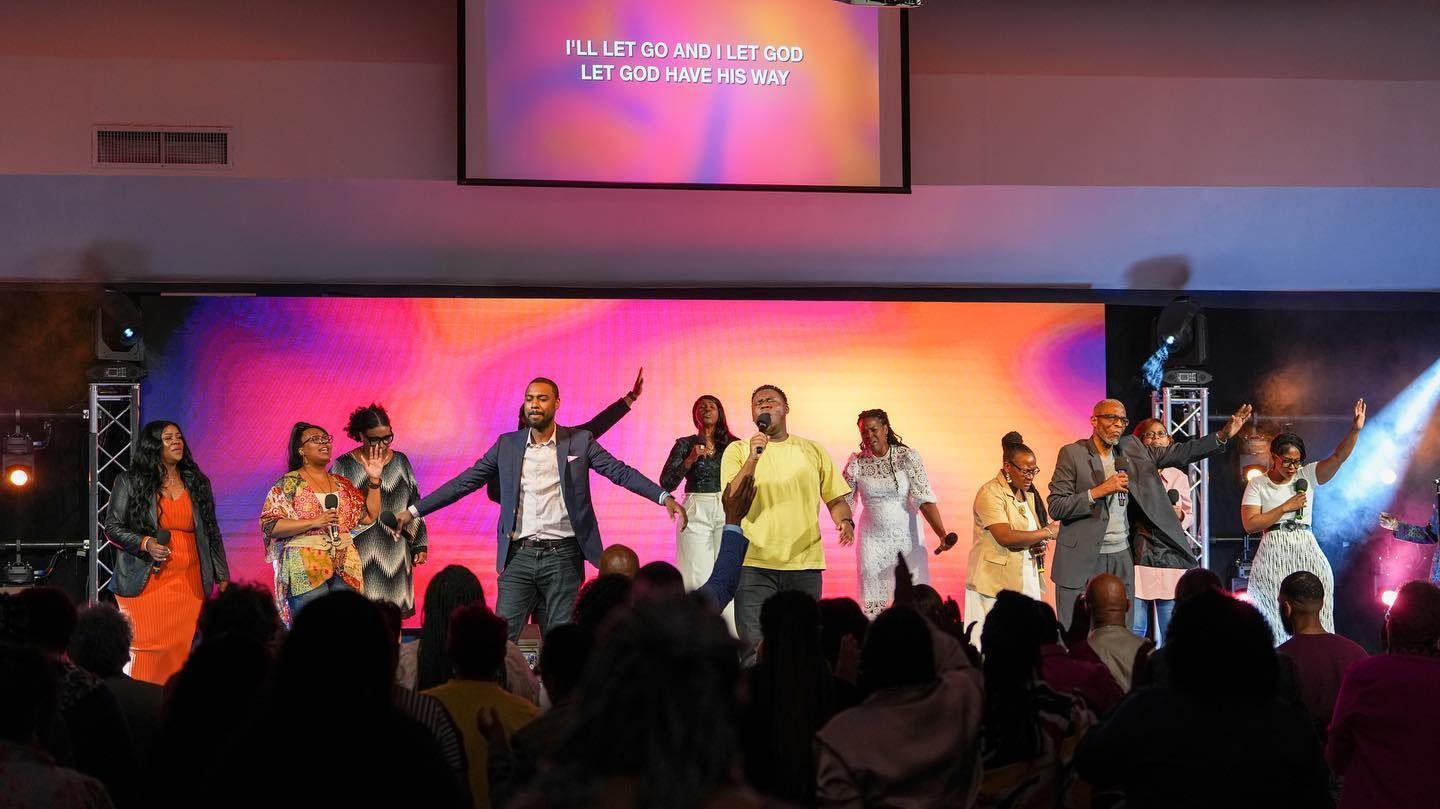 A group of people are standing on a stage holding hands and singing into microphones.