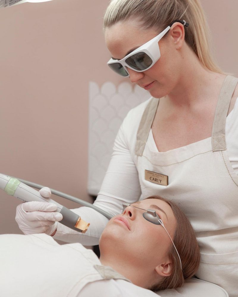 Woman Receiving Laser Treatment to Her Face; a Medical Professional is Attending — Eternal Radiance in Strathmore, VIC