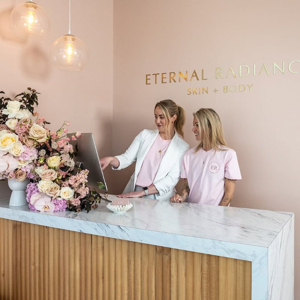 Two Women at a Reception Desk, One Pointing at a Computer — Eternal Radiance in Strathmore, VIC