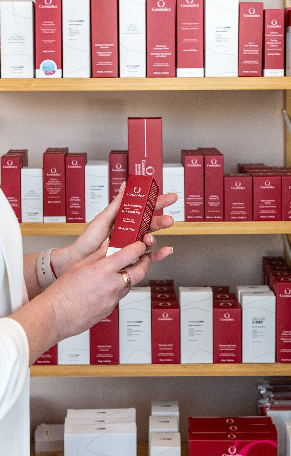 Woman Using Red Light Therapy Device on Face, Holding Skincare Cream — Eternal Radiance in Strathmore, VIC