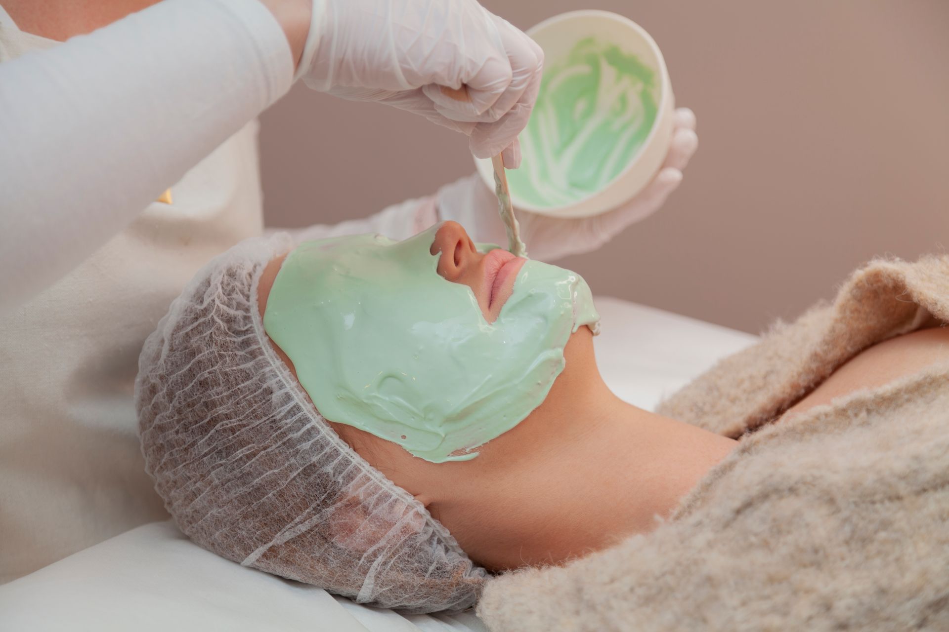 Two Women With Face Masks, Holding Cucumber Slices, Lying on White Surface — Eternal Radiance in Strathmore, VIC